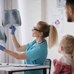 daktarė rodo plaučių rentgenus tėvui su sūnumi